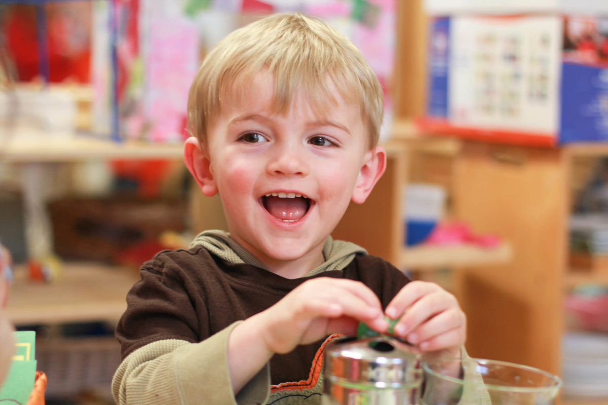 happy montessori boy boy using montessori manipulatives